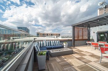 A rooftop patio with a blue couch and wooden deck.